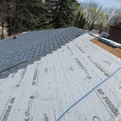 The roof of a house is being covered with a roofing material.