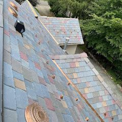 An aerial view of a roof with slate tiles and copper trim.
