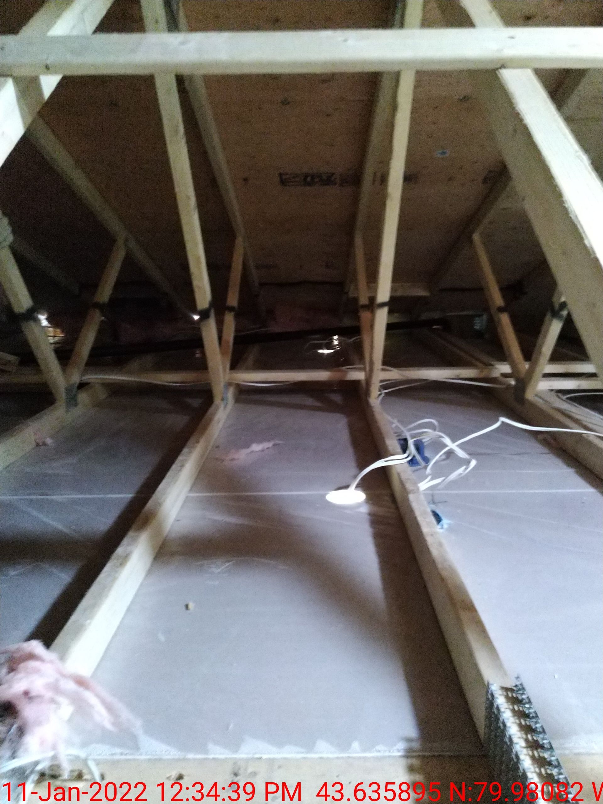 The ceiling of an attic with a lot of wooden beams.
