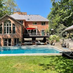 A large brick house with a large swimming pool in front of it.