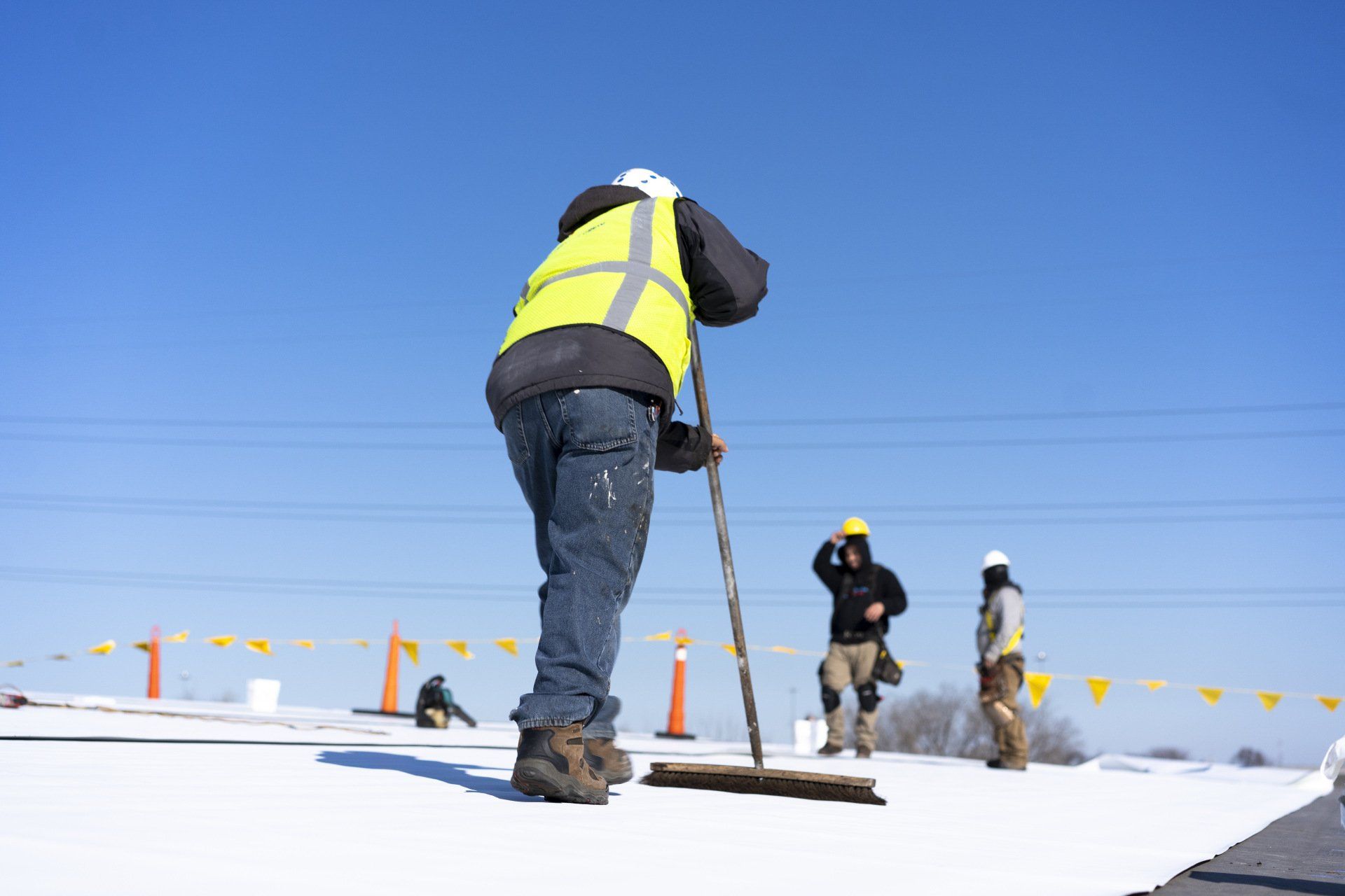 A man is sweeping the snow on a roof with a broom.