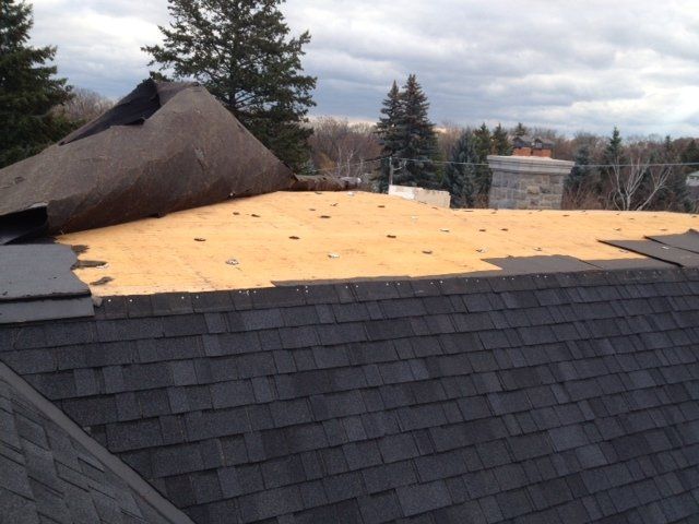 A roof with shingles being installed and a chimney in the background