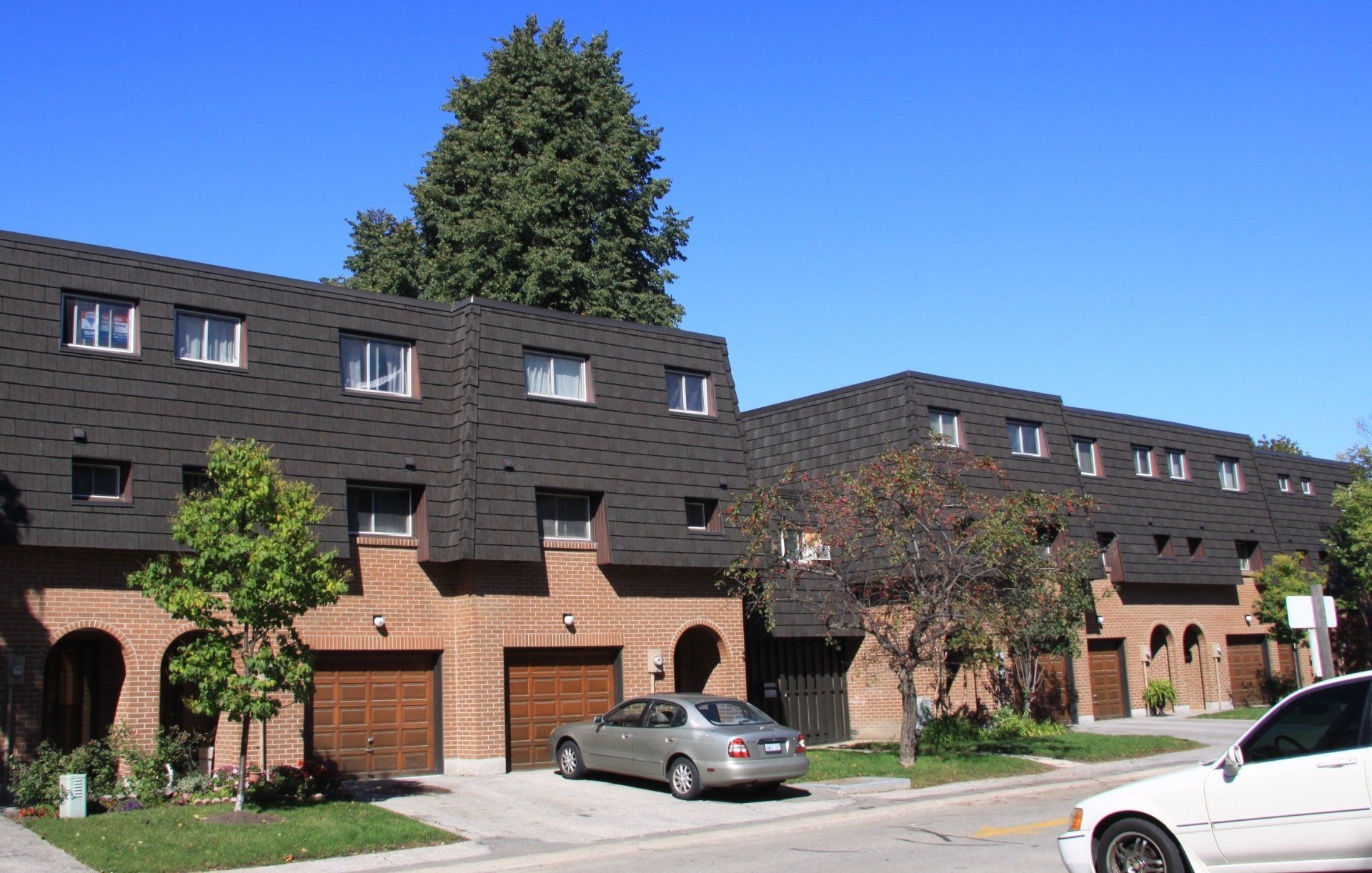 A white car is parked in front of a row of apartment buildings