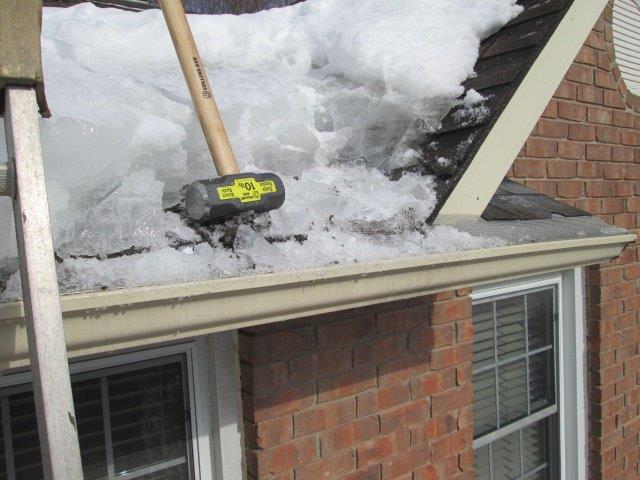 A hammer is being used to remove snow from a roof