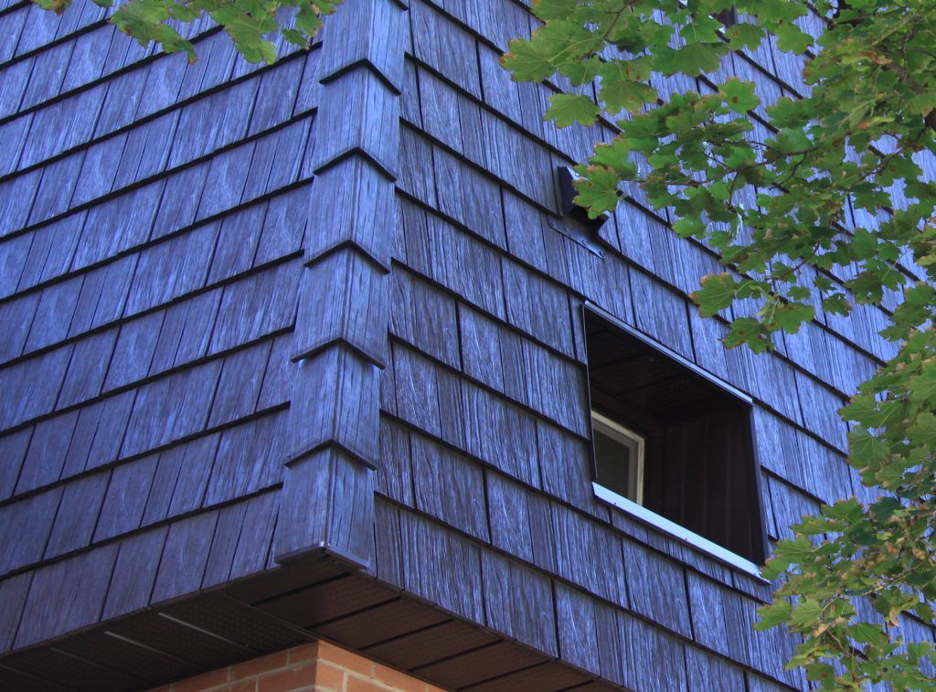 A blue building with a window and a tree in the background