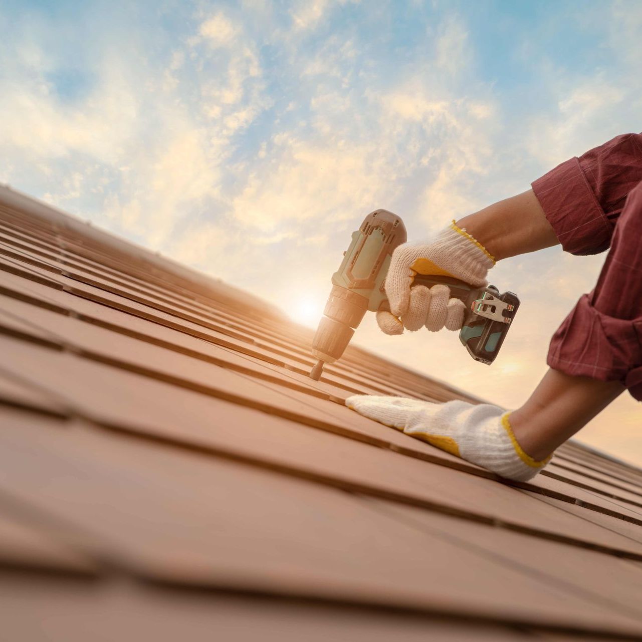 A person is working on a roof with a drill.
