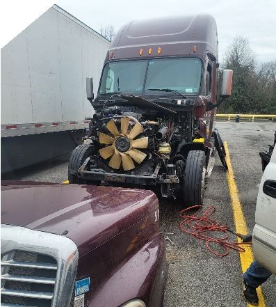 A semi truck with its hood up is parked in a parking lot.