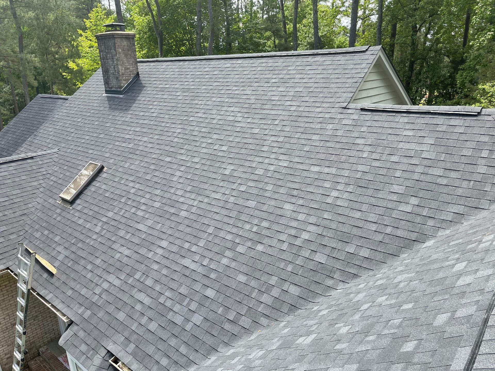 The roof of a house with a skylight and a chimney.