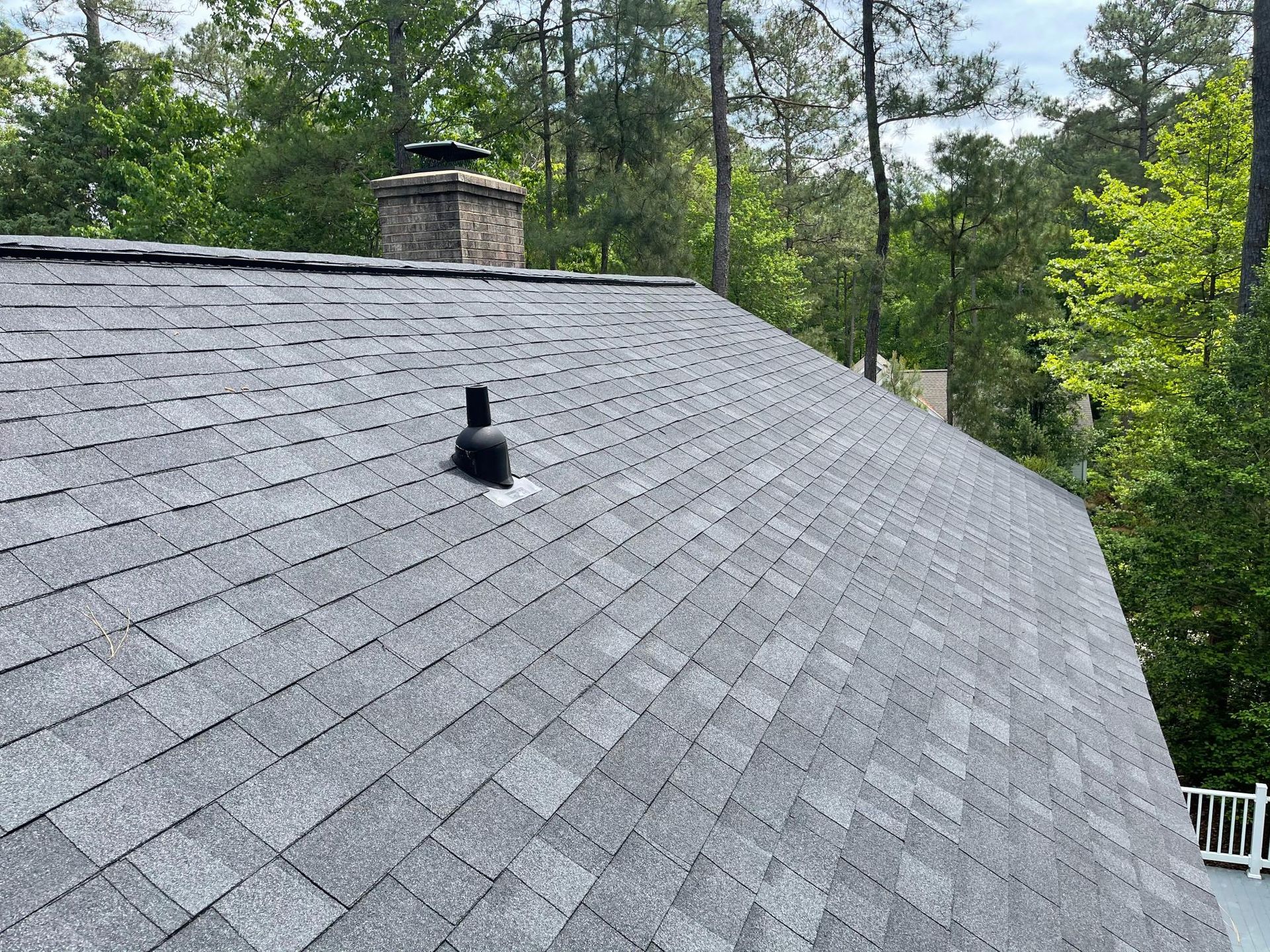 A roof with a chimney on it and trees in the background.