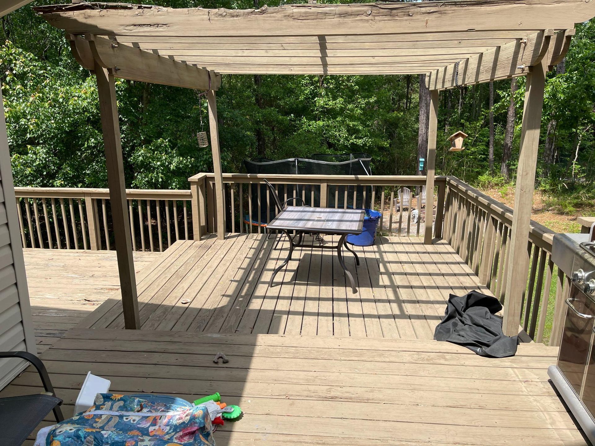 A wooden deck with a table and chairs under a pergola.