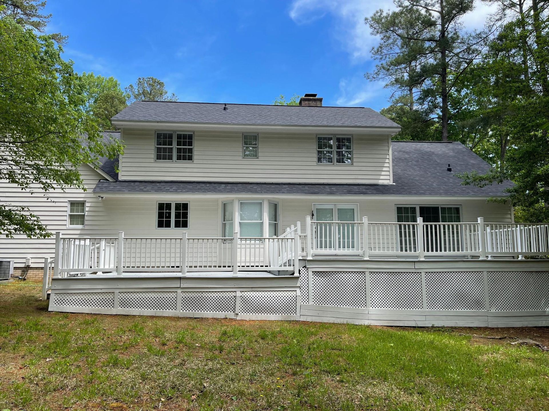 The back of a white house with a large deck.