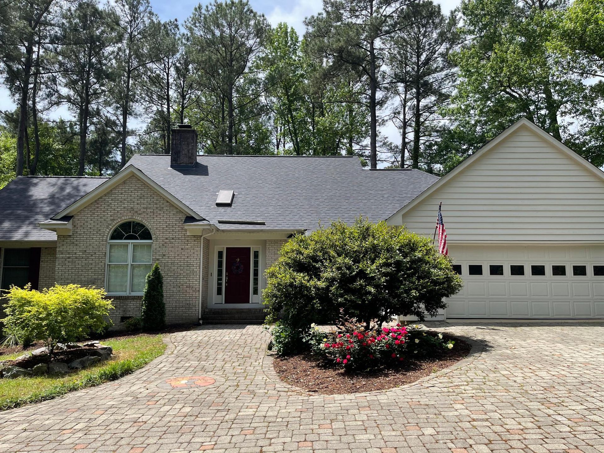 A white house with a brick driveway and a garage