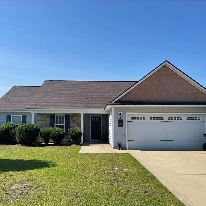 A white house with a brown roof and a white garage door