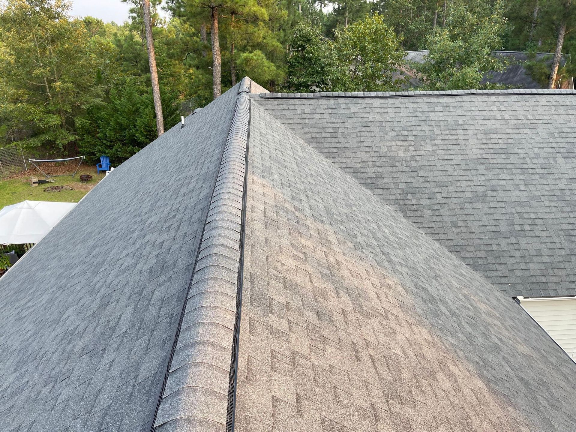 A close up of a roof with a lot of shingles and trees in the background.