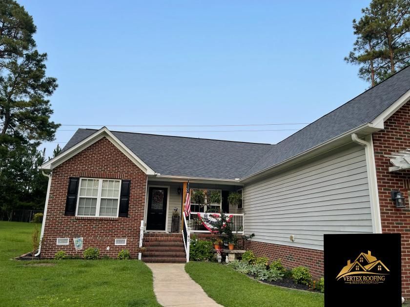 A brick house with a gray roof and white siding