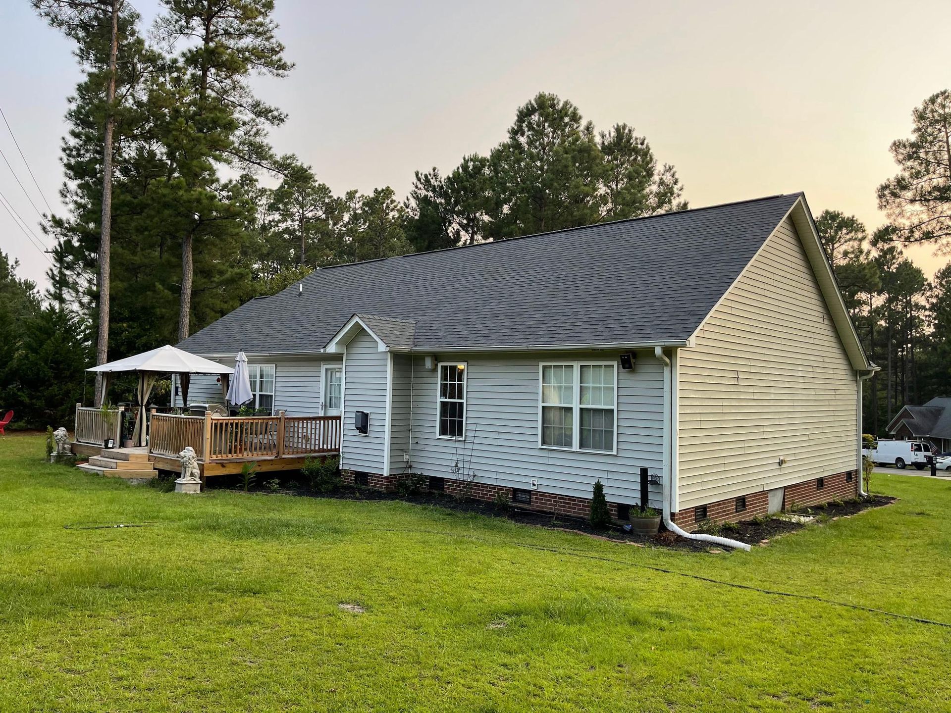 A white house with a black roof is sitting on top of a lush green field.