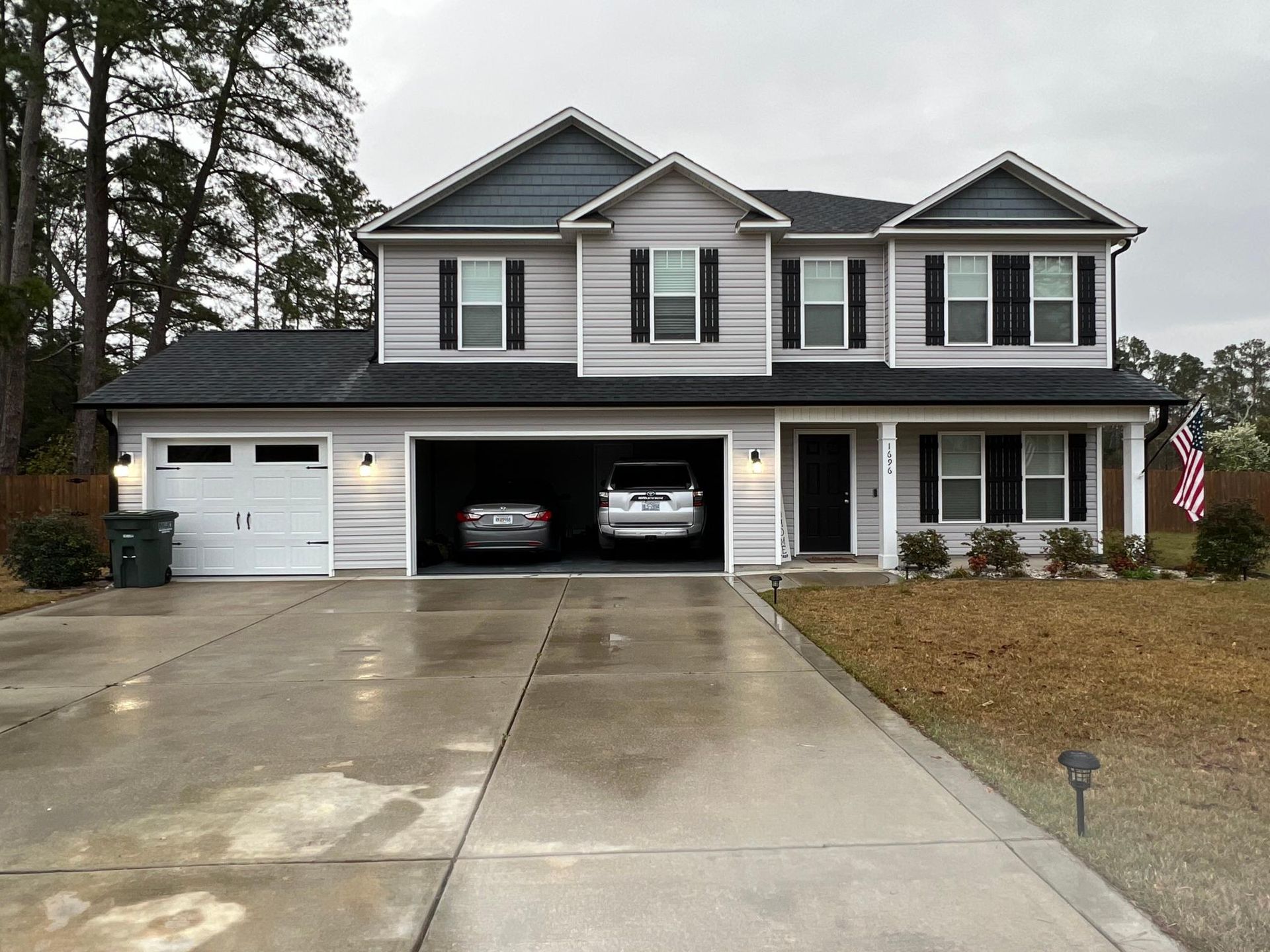 Two cars are parked in the driveway of a large house.