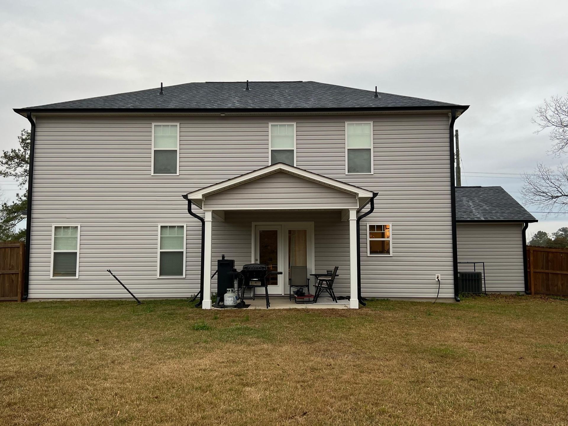 The back of a house with a porch and a lot of windows.