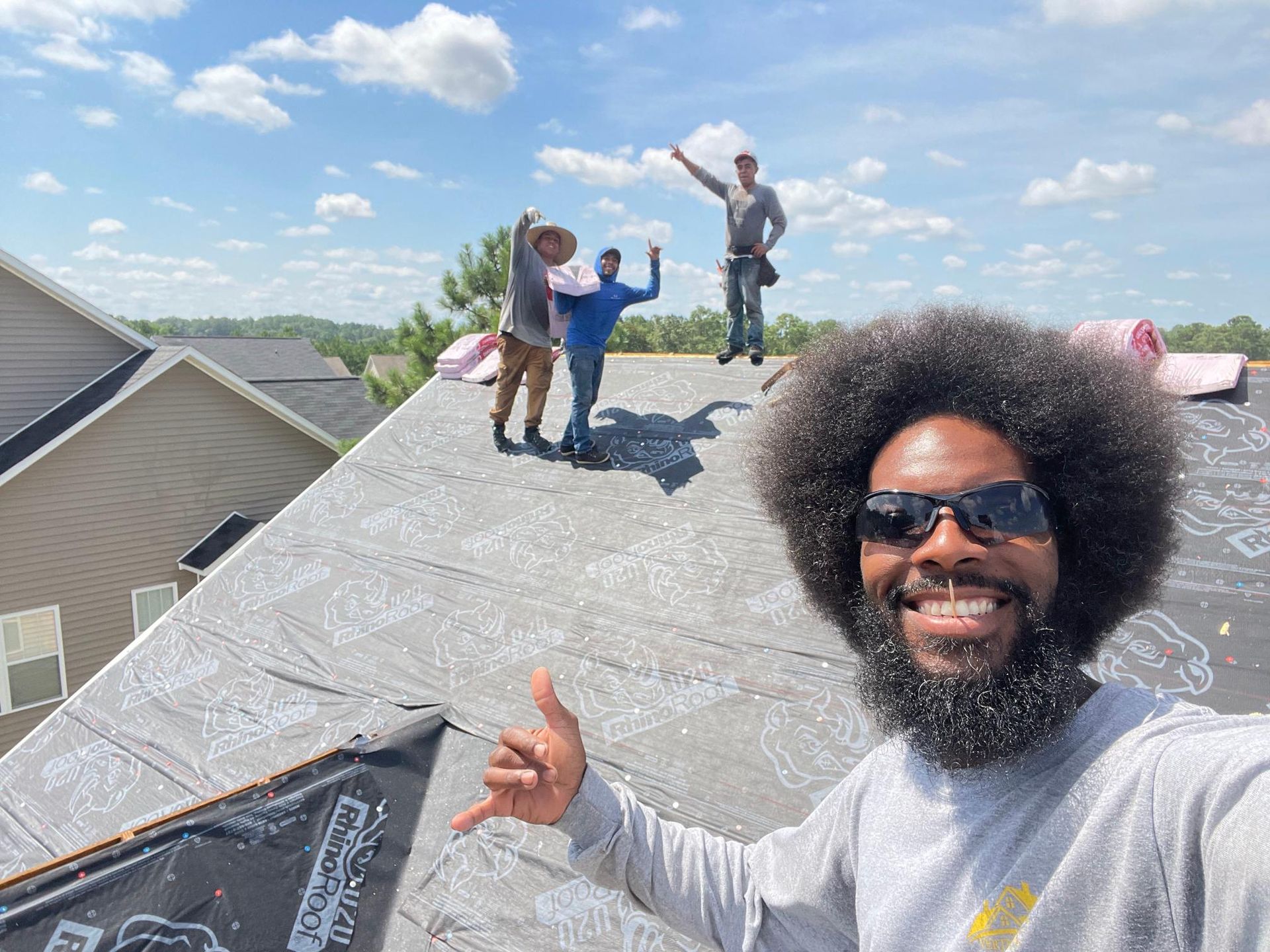 A man with an afro is standing on top of a roof giving a thumbs up.