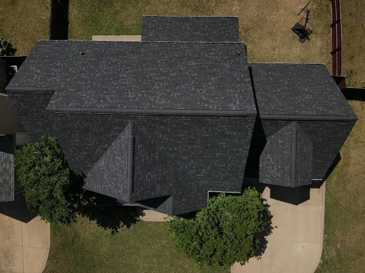 An aerial view of a large house with a black roof.