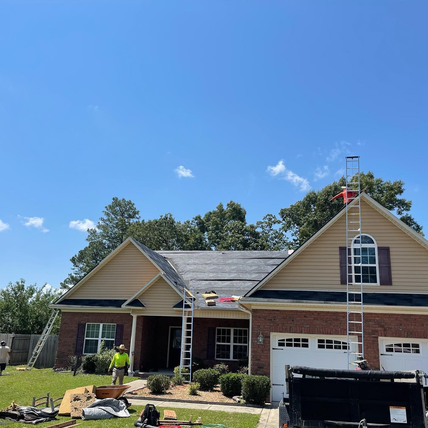 A man is standing on a ladder on the roof of a house.