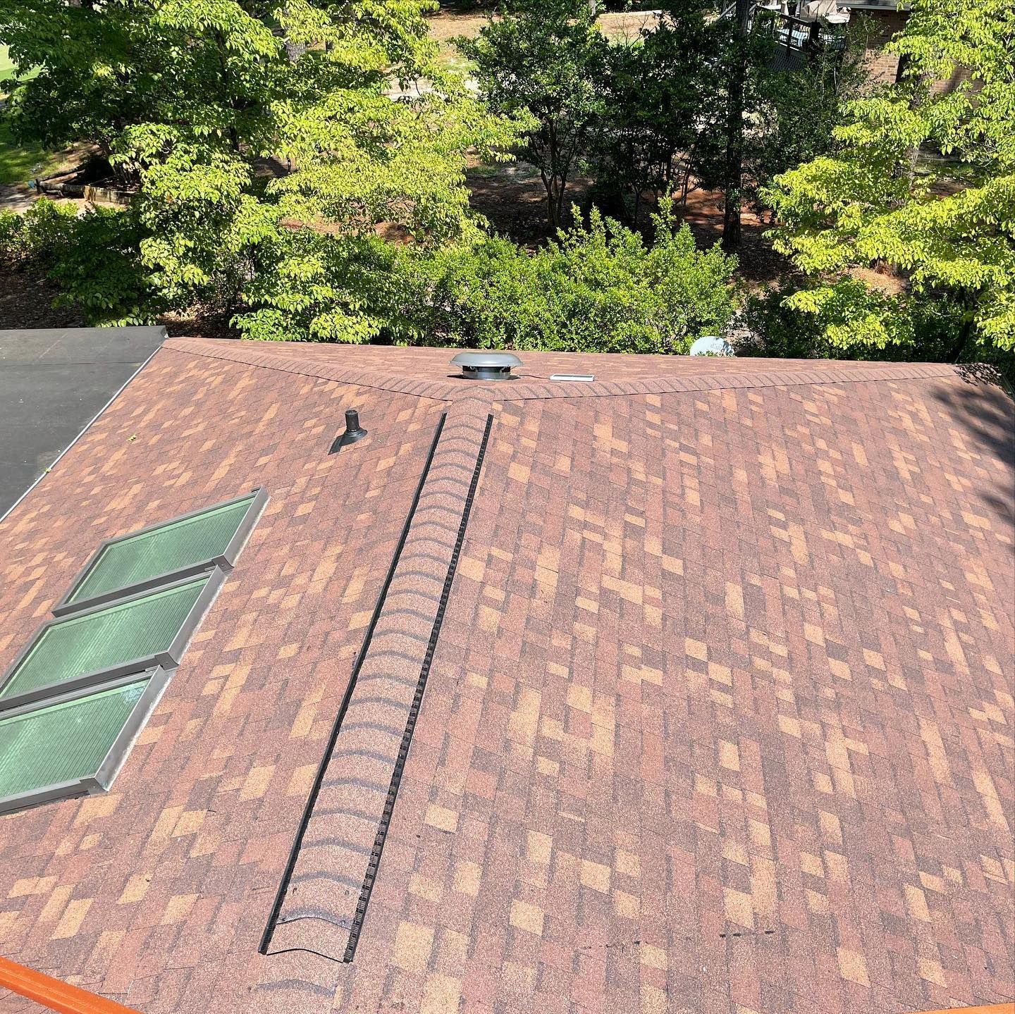 A roof with a ladder on it and trees in the background.