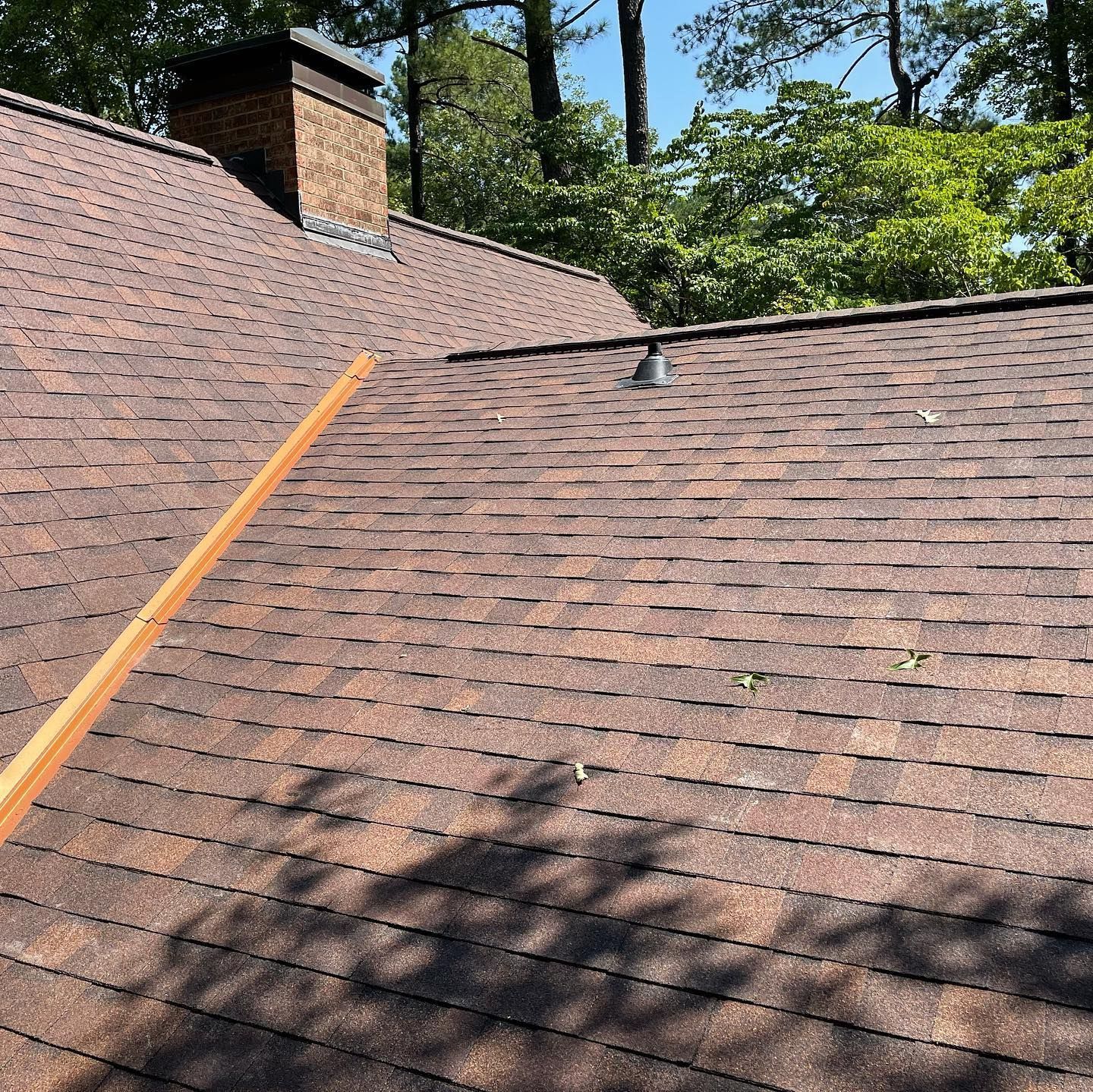 A roof with a chimney and trees in the background
