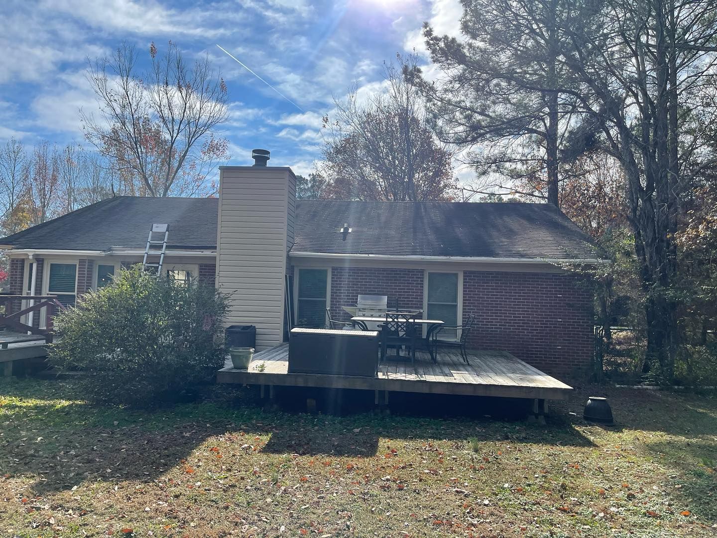 A brick house with a deck and a hot tub in the backyard.