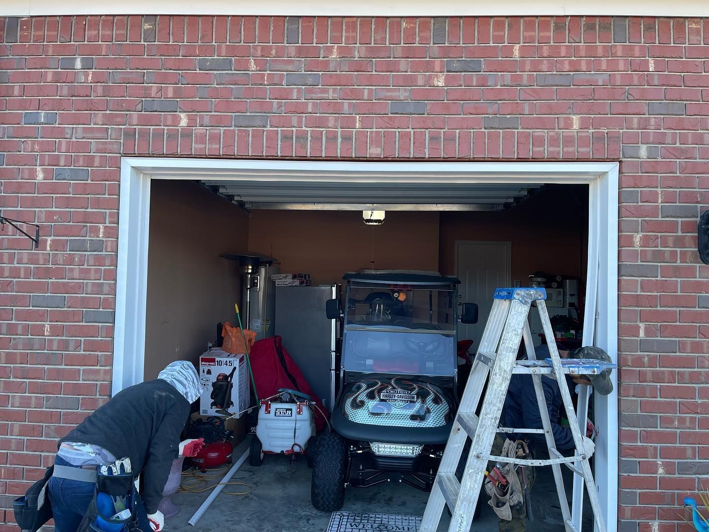 A man is working on a garage door with a golf cart in it.