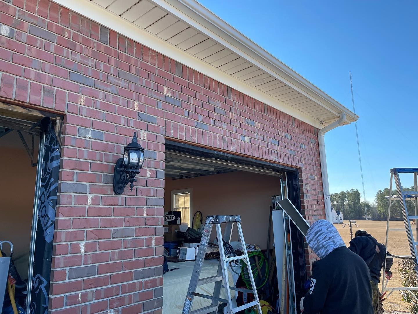A man is opening a garage door with a ladder.