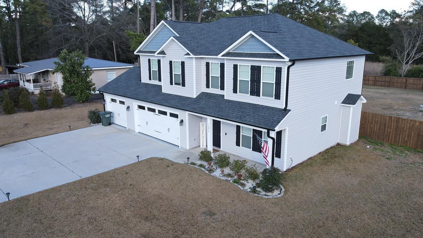 An aerial view of a large white house with a blue roof.