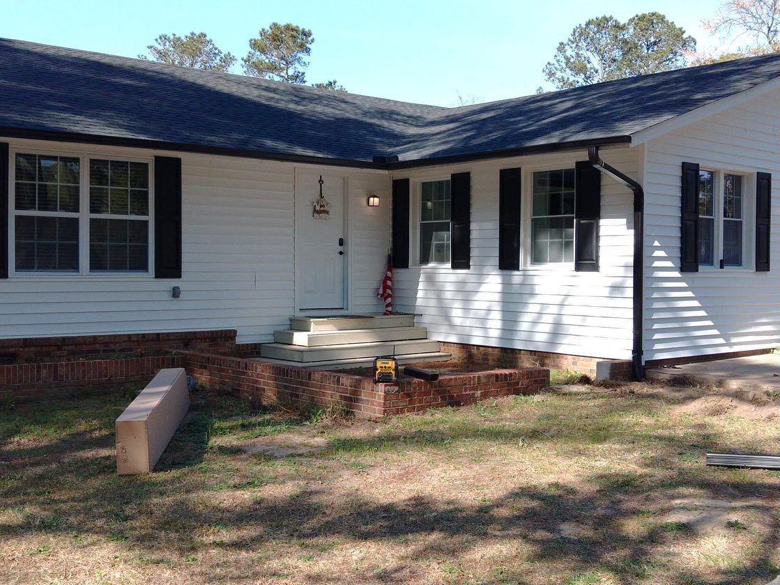 A white house with black shutters and a black roof