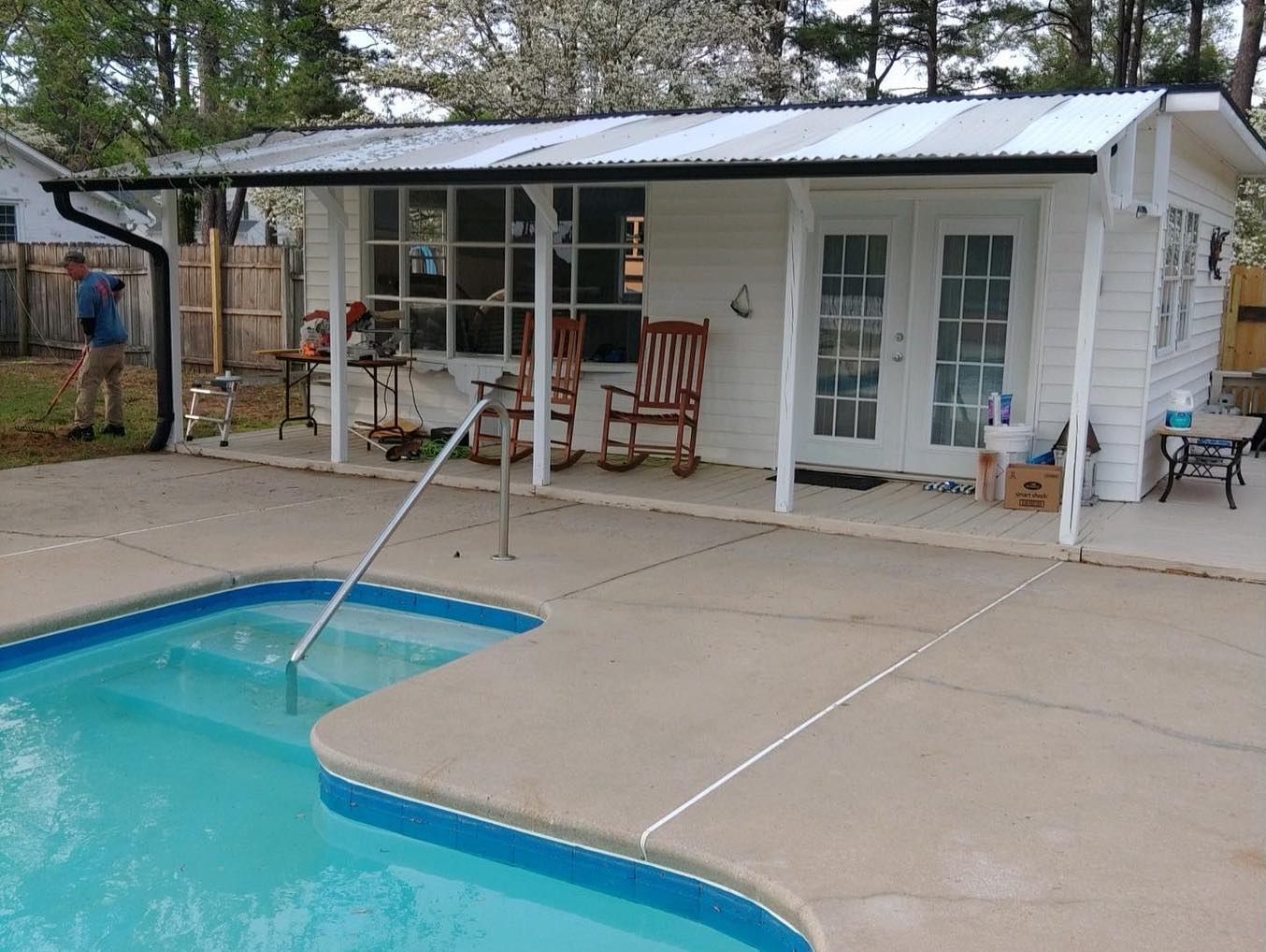 A white house with a porch overlooking a swimming pool