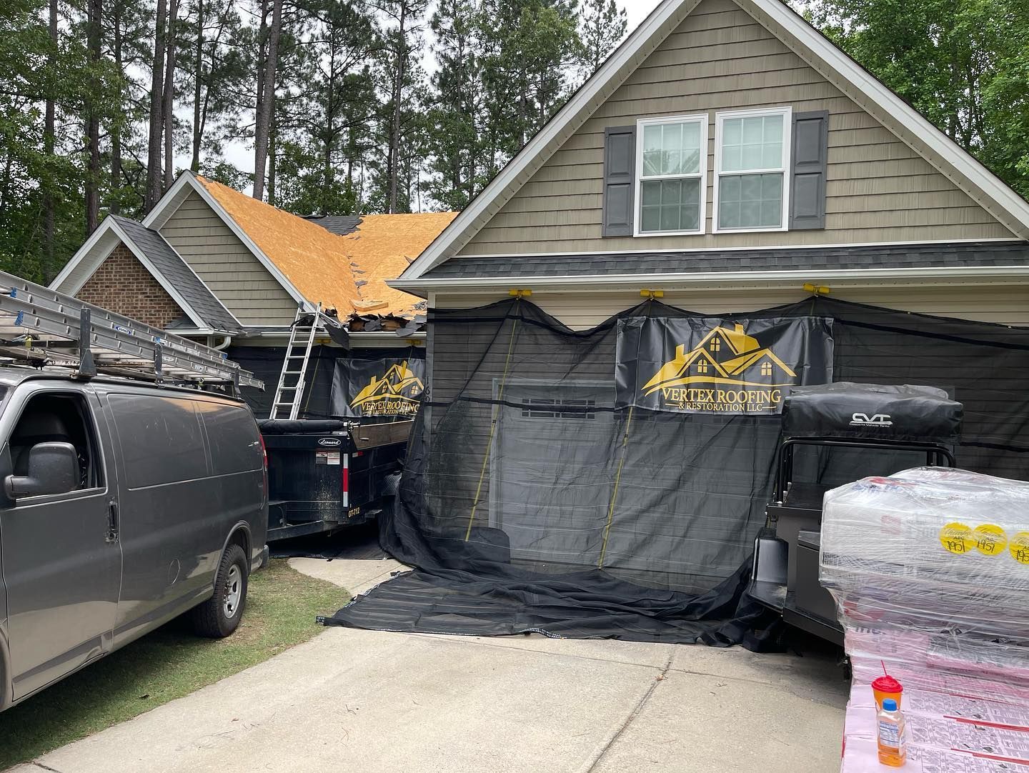 Two vans are parked in front of a house that is being remodeled.