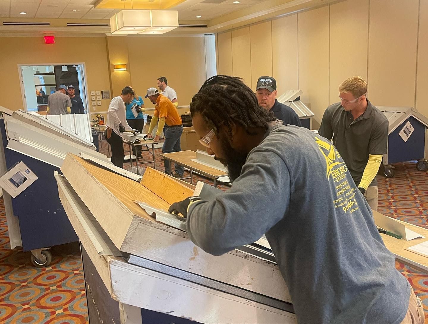 A group of men are working on a piece of wood in a room.