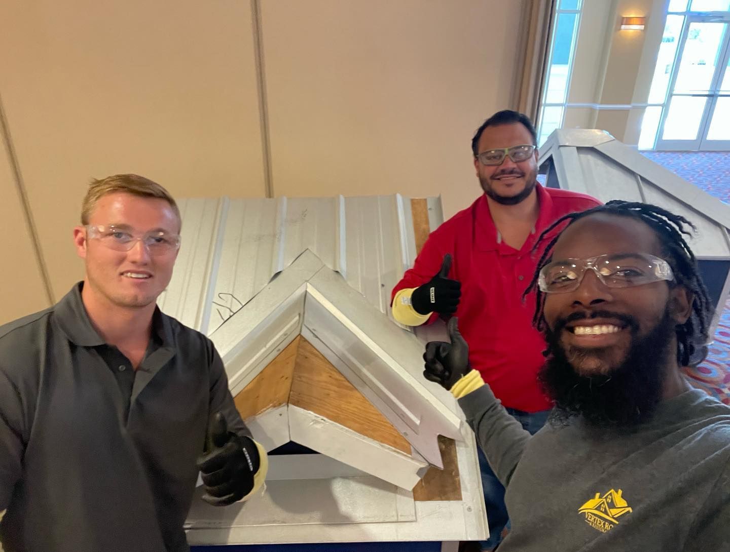 Three men are standing next to each other holding a piece of metal.