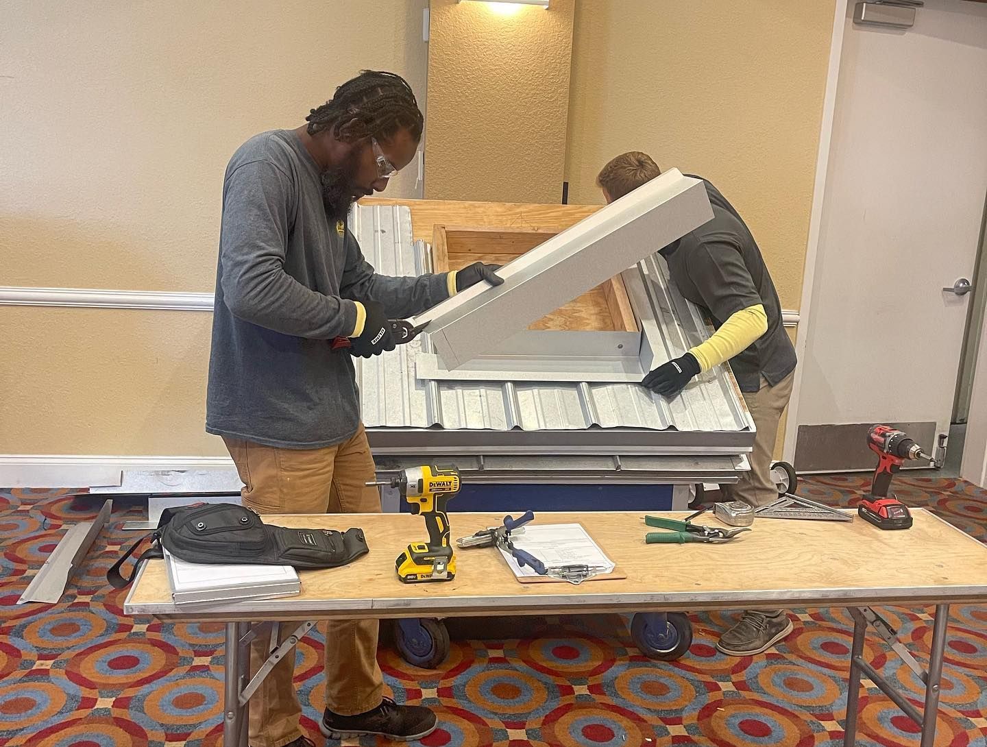Two men are working on a table in a room.