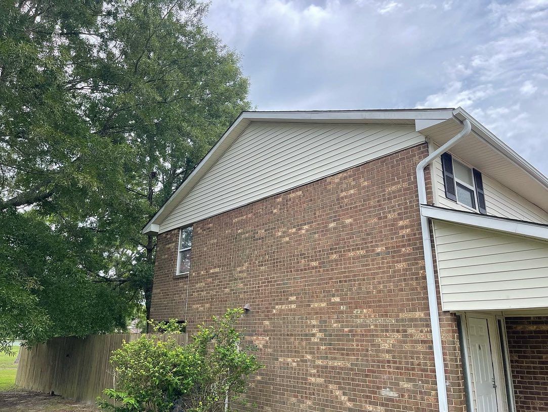 A brick house with a white roof and a tree in front of it.