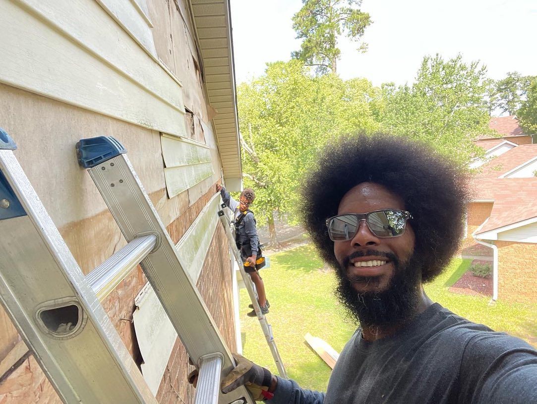 A man is standing on a ladder next to a house.