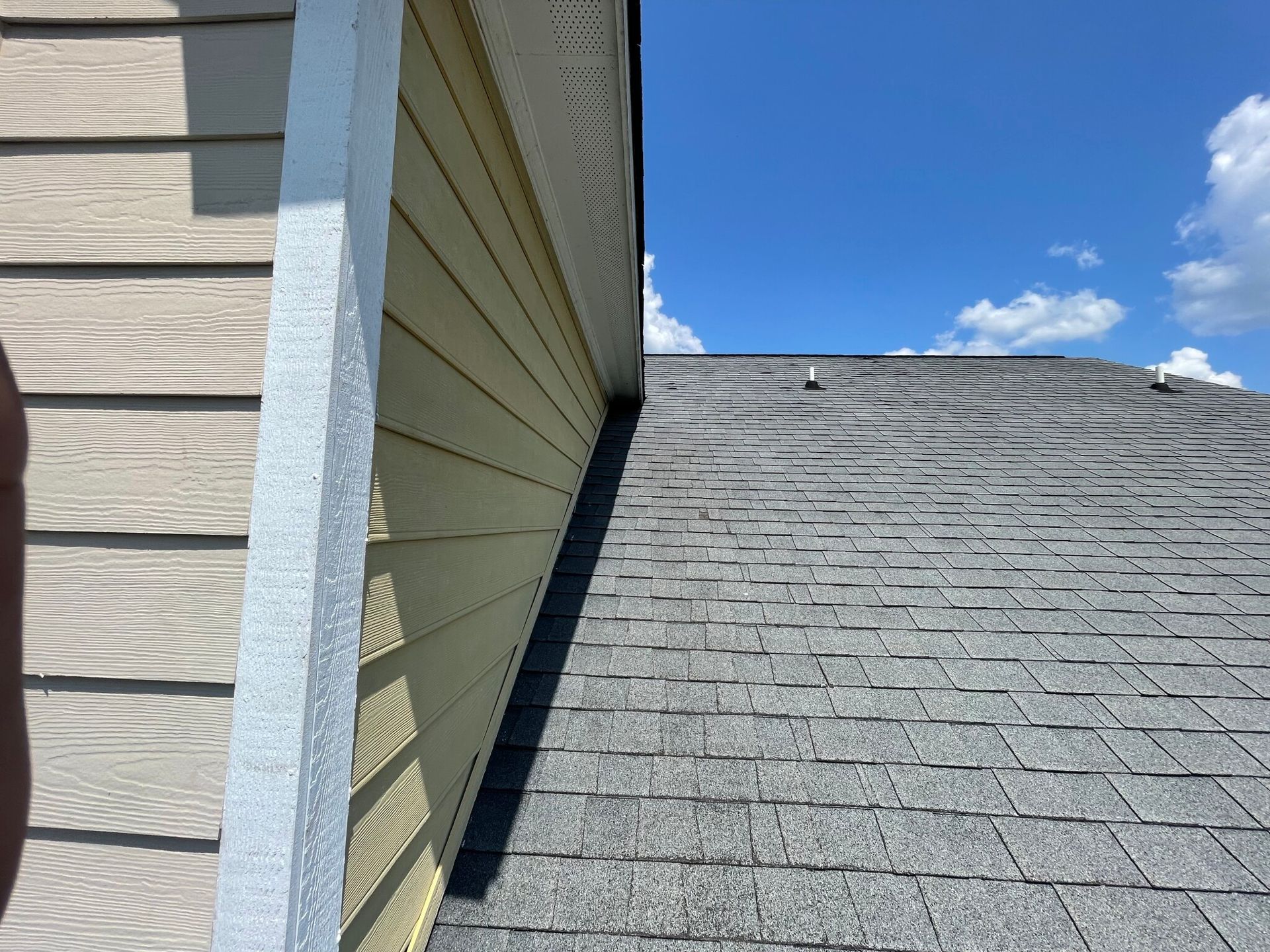 A close up of a house with a roof and a blue sky in the background.