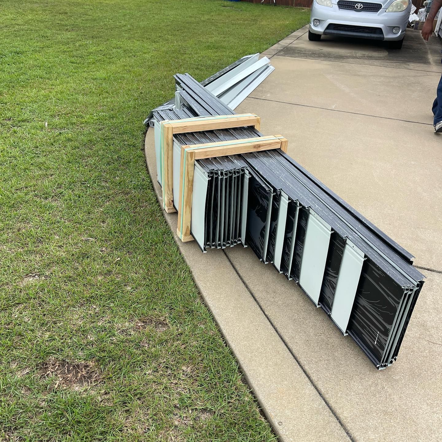 A stack of metal pieces sitting on a sidewalk next to a car.