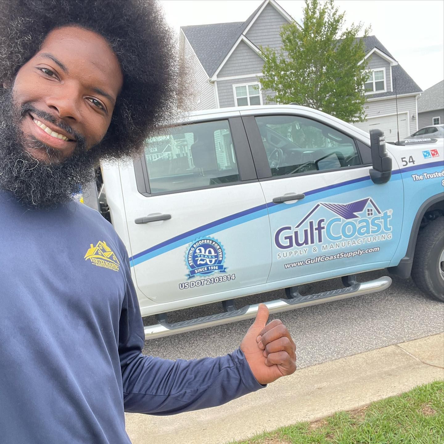 A man is giving a thumbs up in front of a gulf coast truck.