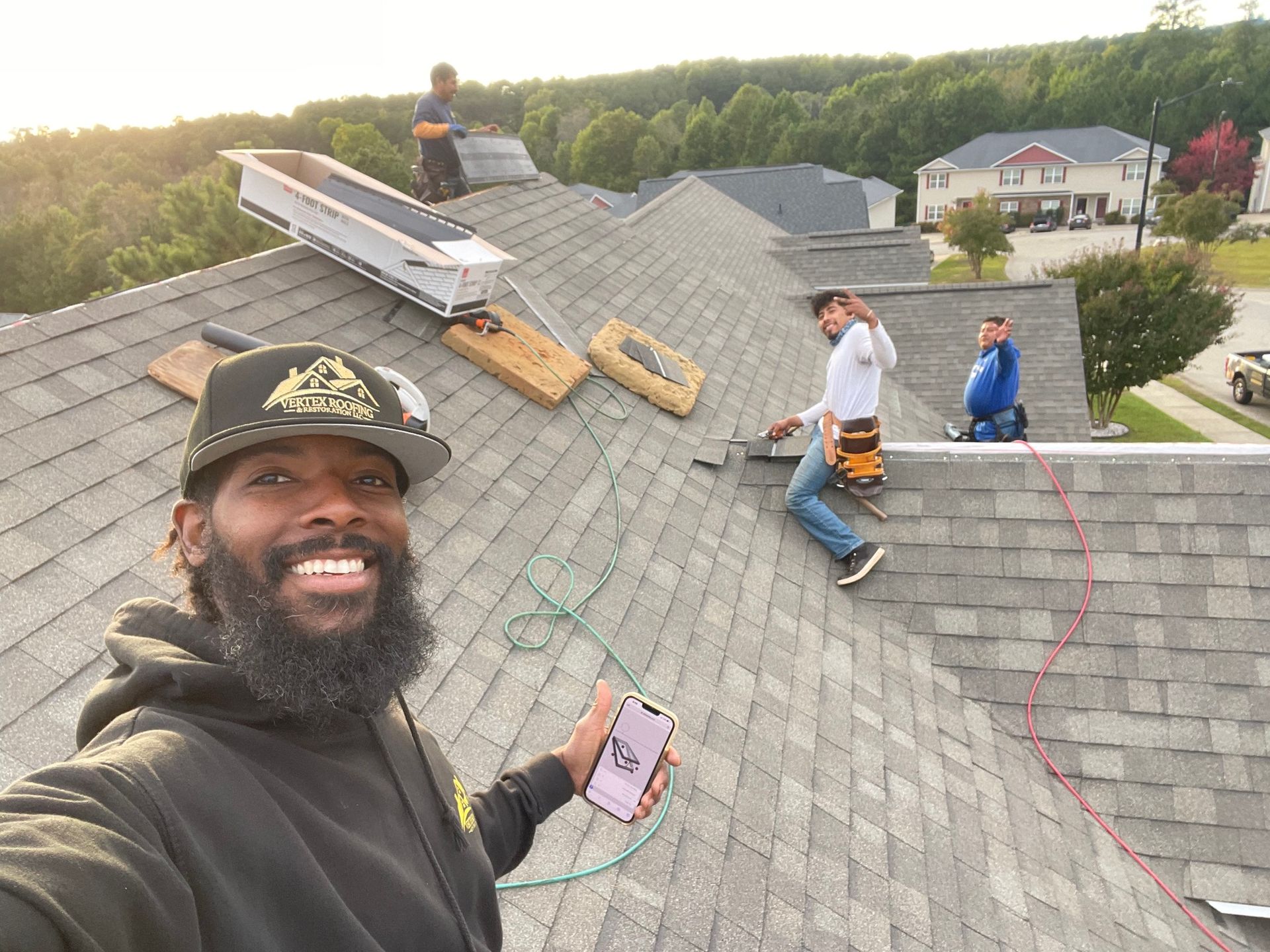 A man is standing on top of a roof holding a cell phone.