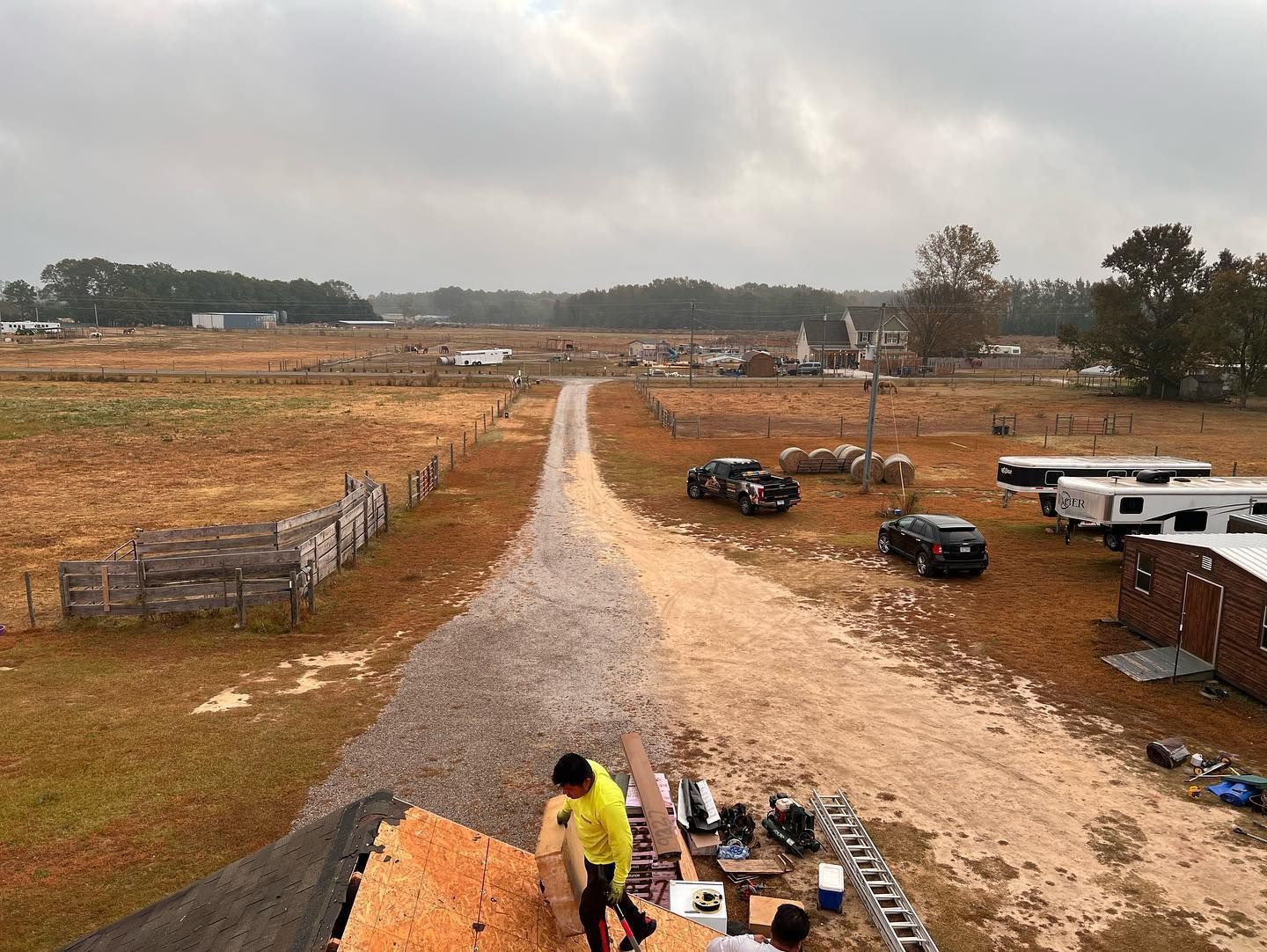 A group of people are working on a roof in a field.