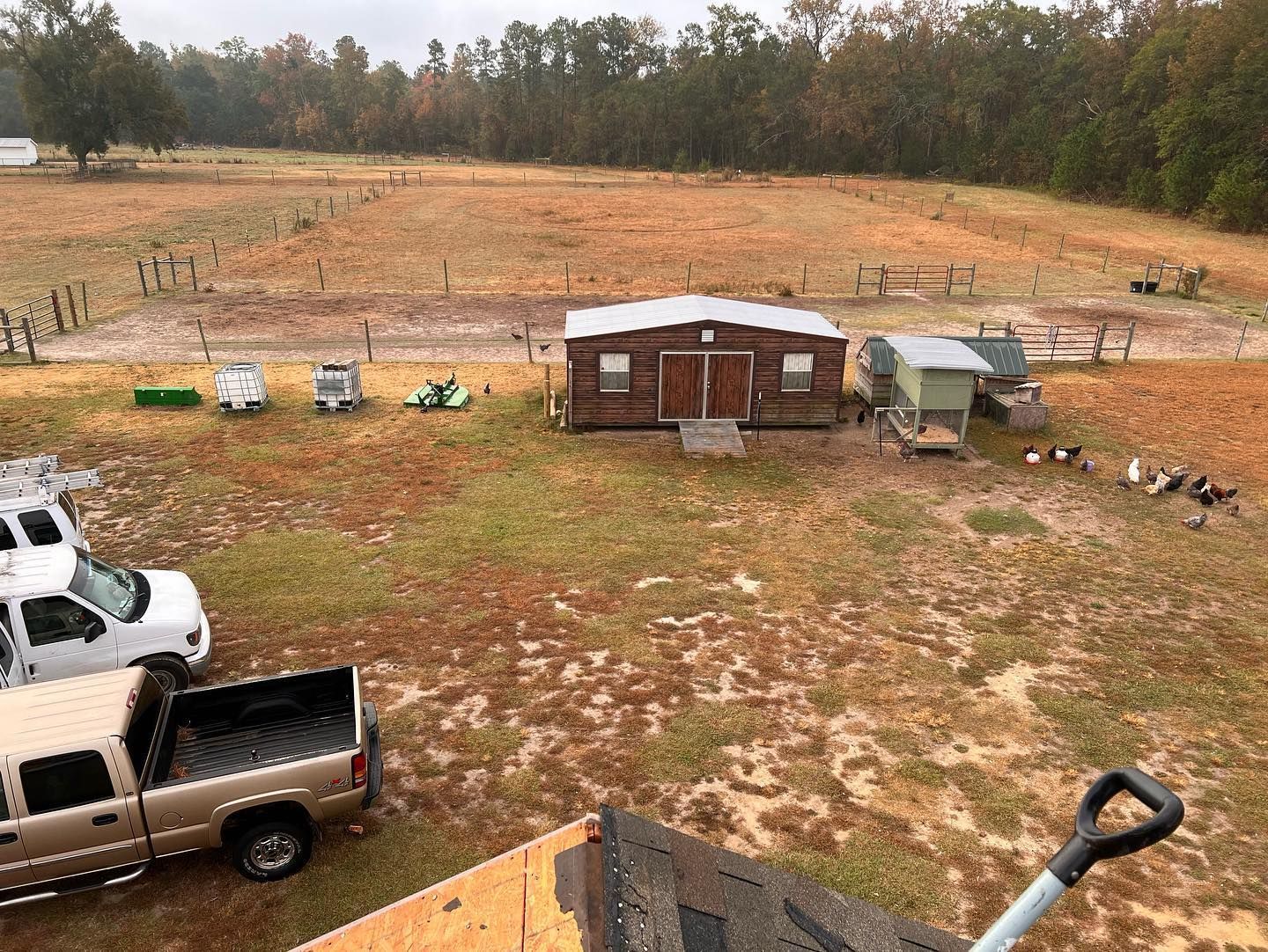 A truck is parked in a field next to a chicken coop.