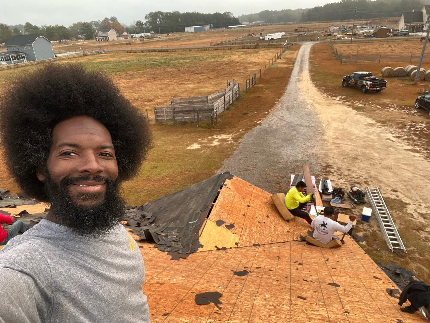 A man with a beard is standing on top of a wooden roof.