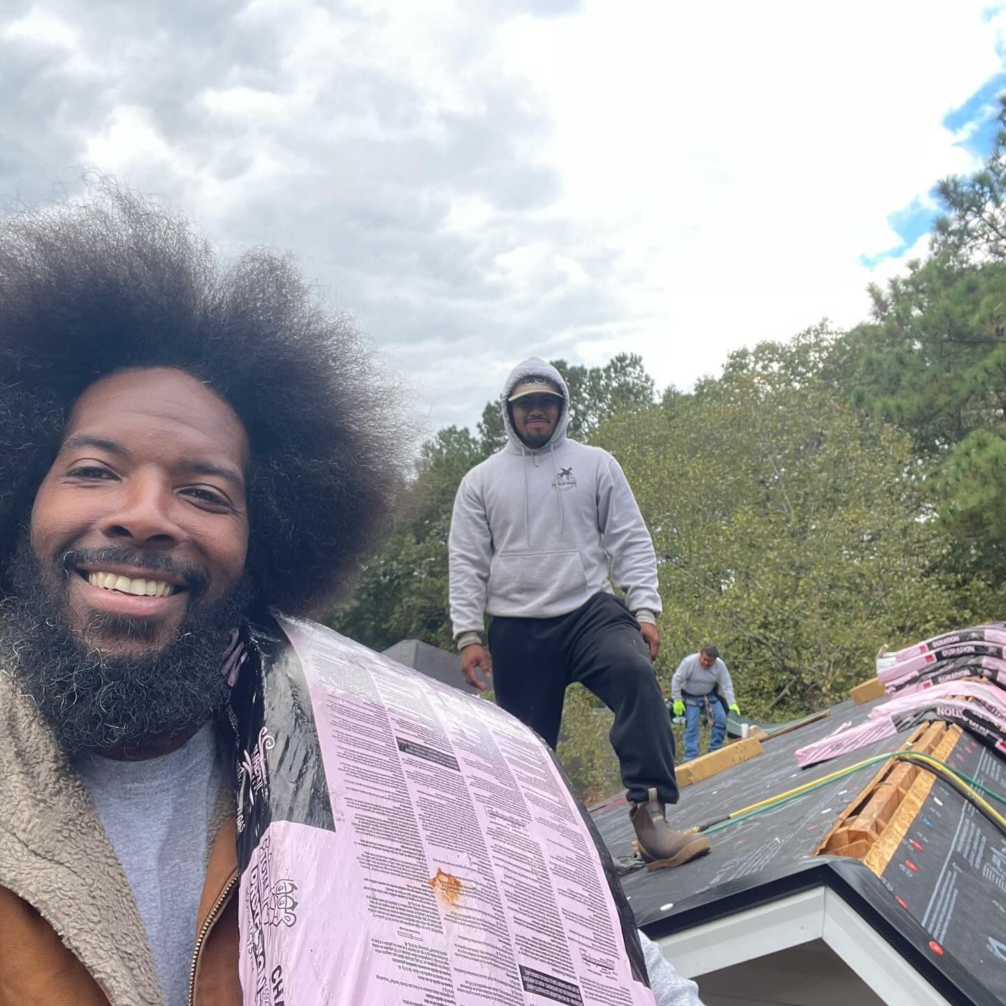 A man with a beard is smiling while standing on a roof.