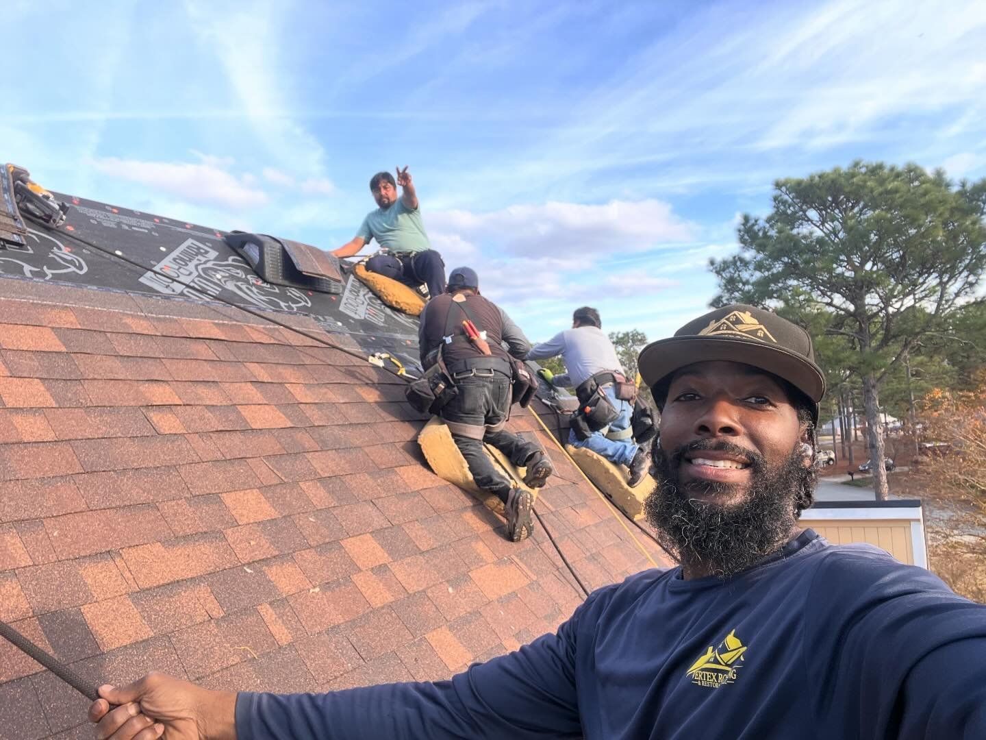 A man is standing on top of a roof holding a hammer.