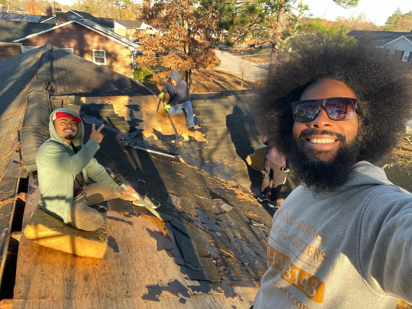 A man with a beard is taking a selfie on the roof of a house.