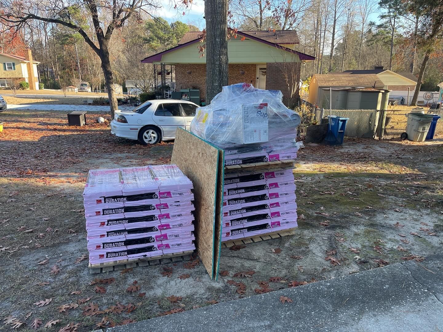 A bunch of bags of dog food are stacked on top of each other in front of a house.